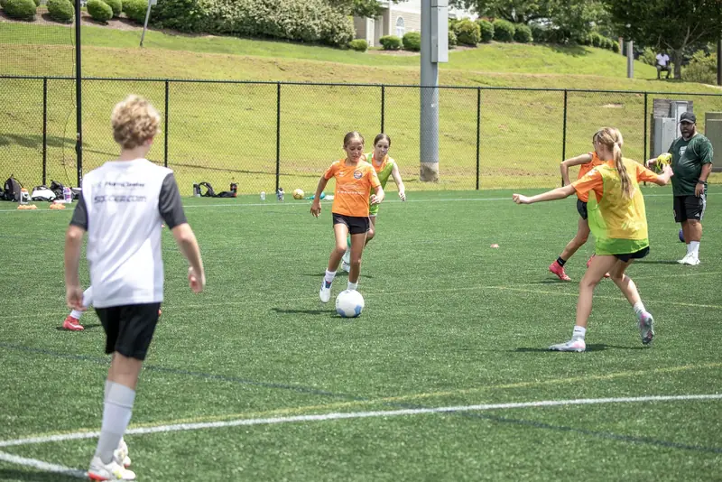 Players in training bibs run a passing pattern