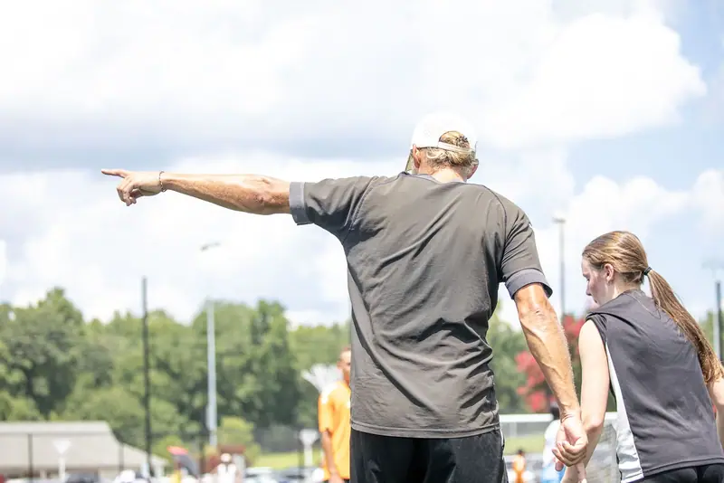 A coach points across the field to organise a drill