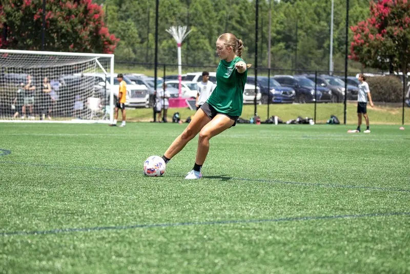 A player in green strikes the ball toward goal