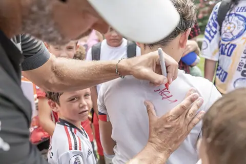 A coach signs a young player's shirt after a clinic