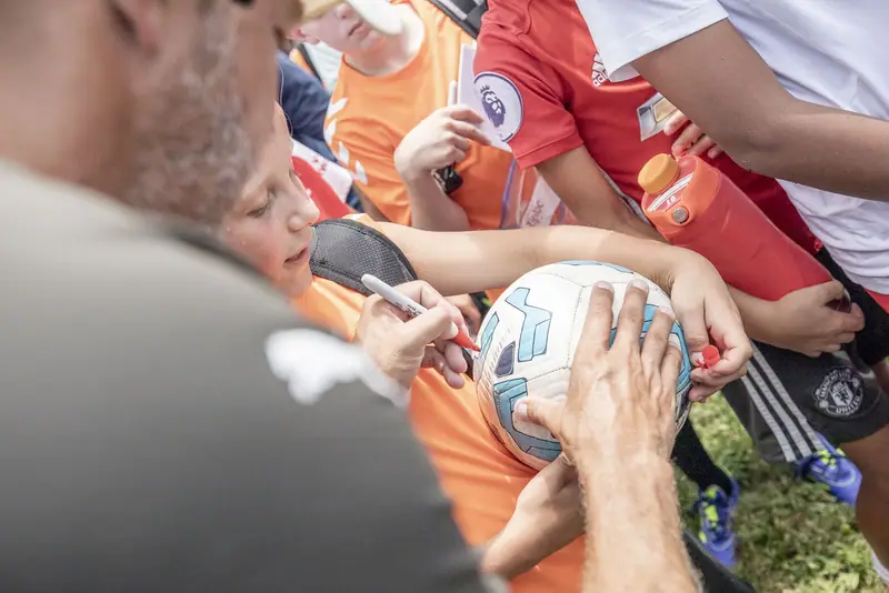 Players crowd around a coach signing a ball